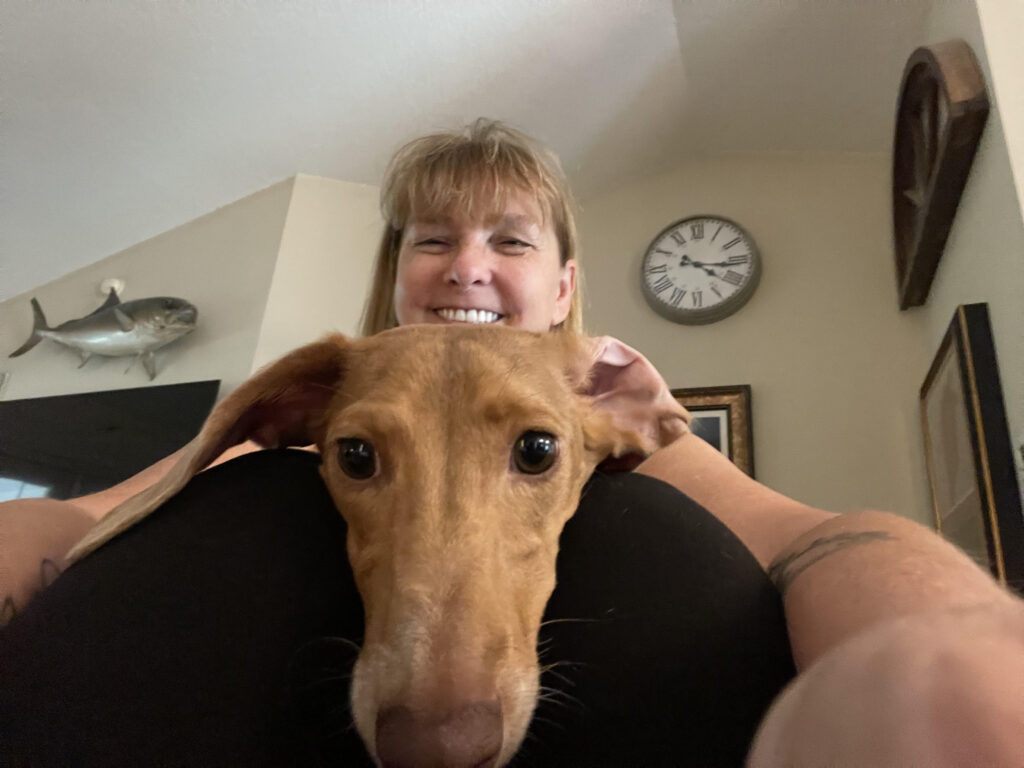 A woman is holding the head of a dog.