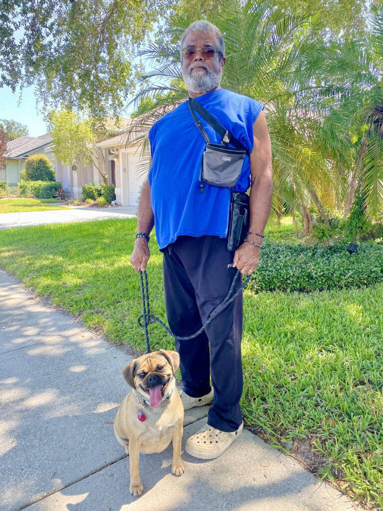 A man and his dog are walking down the street.