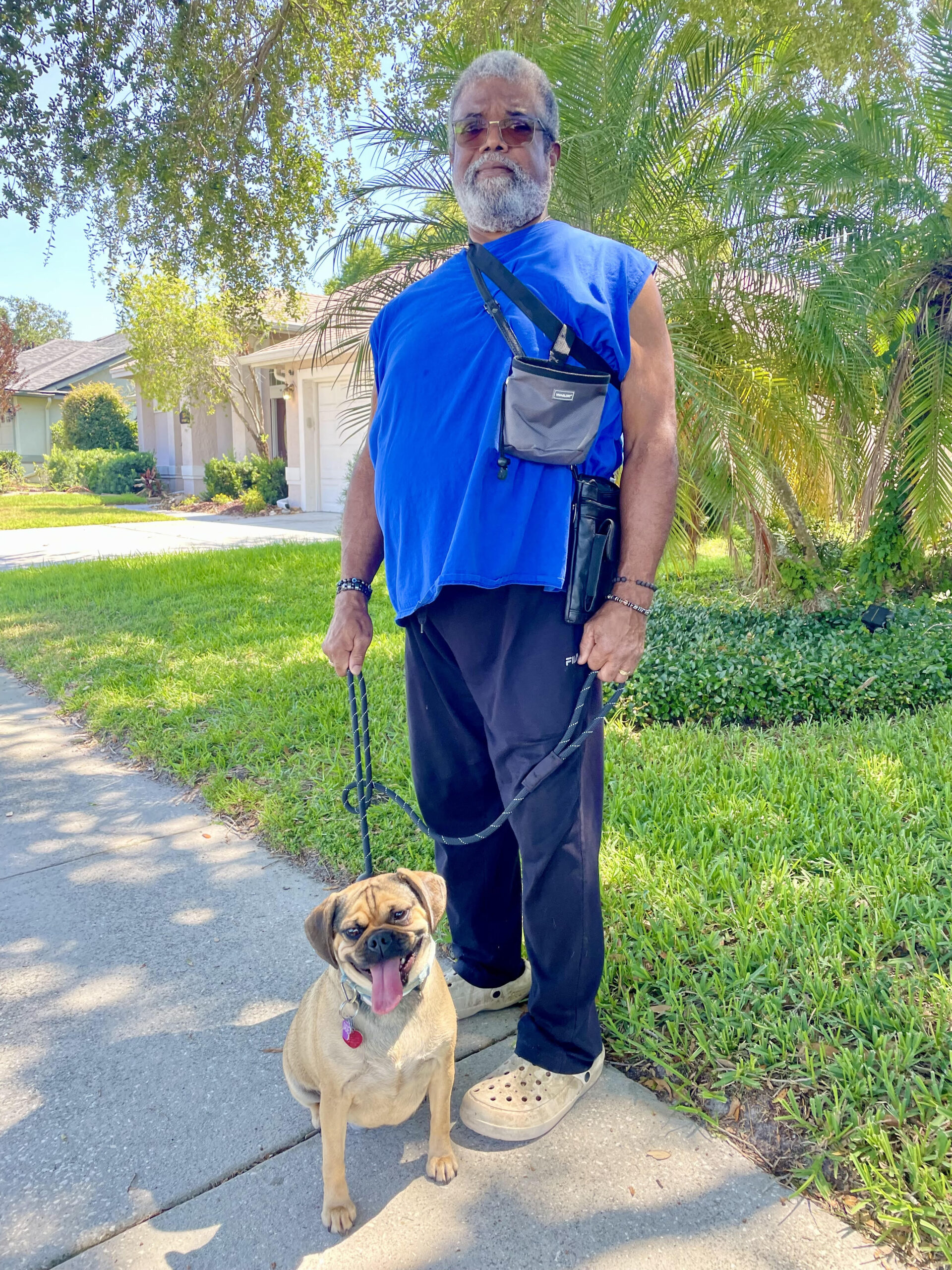 A man and his dog are walking down the street.