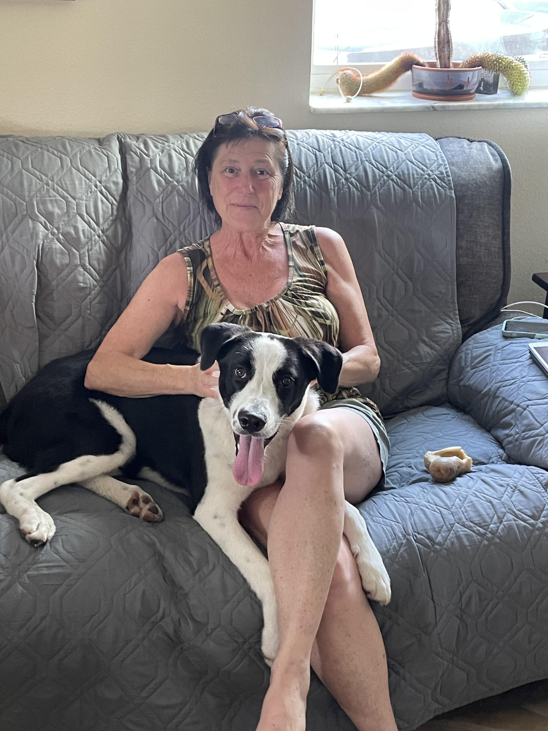 A woman sitting on the couch with her dog.