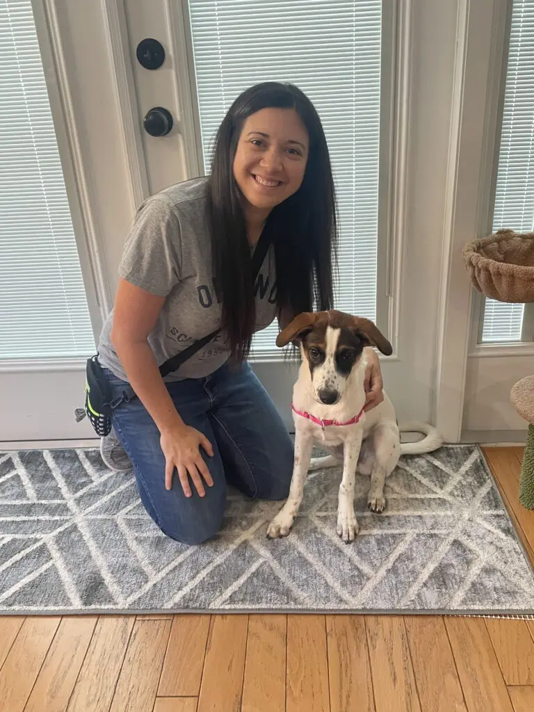 A woman kneeling down next to her dog.