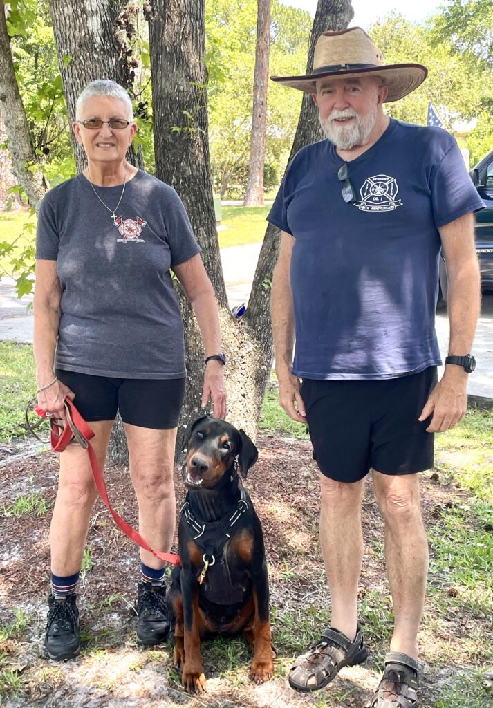 A man and woman standing next to a dog.